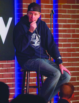 man with microphone sitting on stage in front of audience