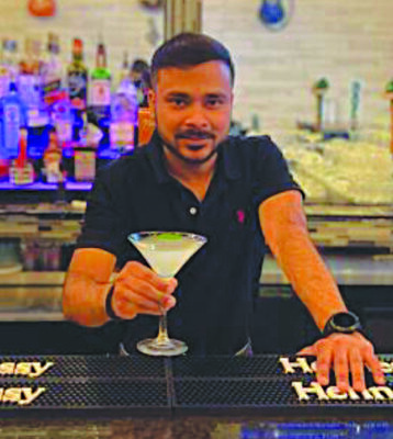 man behind bar holding out cocktail