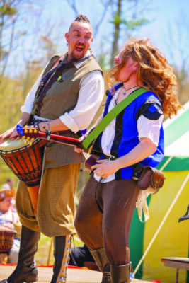 2 costumed musicians at renaissance faire, laughing with each other