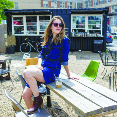 young woman sitting on picnic table outside restaurant on sunny day