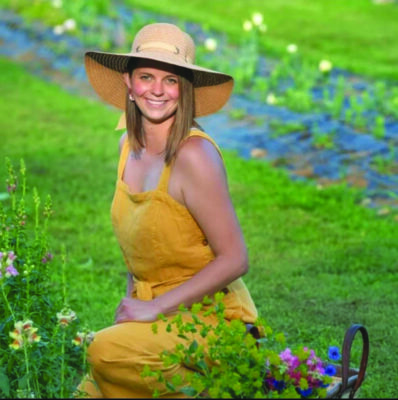 woman in summer dress and hat sitting in garden