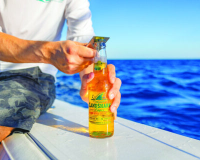 man opening beer bottle on boat