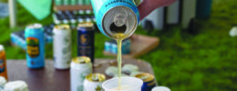 hand pouring beer into plastic cup, outside
