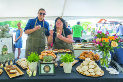man and woman standing behind event table filled with food samples