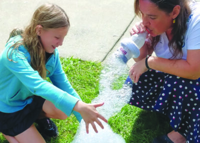 young girl and woman playing with homemade bubble making device