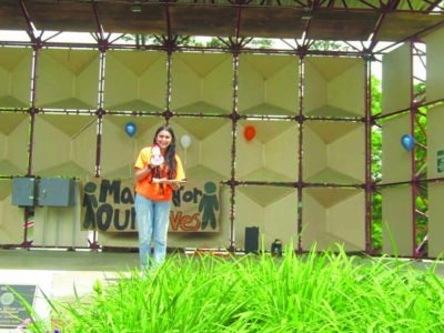 teenage girl with megaphone, giving speech on platform in park