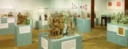 plaster sculptures depicting scenes with people, displayed in cases in gallery