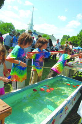 kids in tie-dye shirts fishing in troughs at town fair