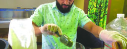 bearded man in restaurant spooning kava into bowl to mix drink