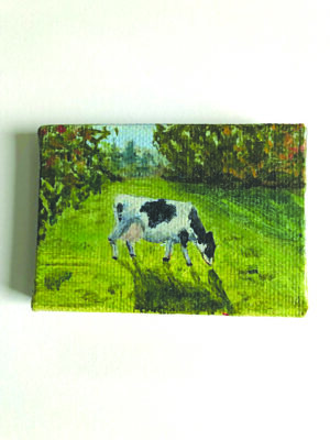small canvas painting depicting a cow eating grass in a sunny field
