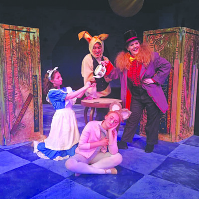 Actors dressed as characters from Wonderland, posing on stage