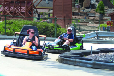 man and woman driving go-karts at a fun park