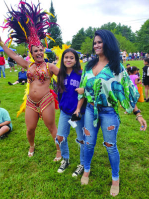 Samba dancer in costume standing with 2 young women