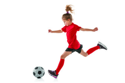 young girl running with soccer ball on blank background