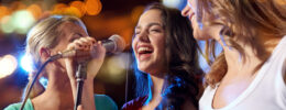 happy young women singing karaoke in night club