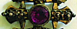 broach in the shape of a square cross with smaller crosses in the corners, round stone of colored glass set in the middle