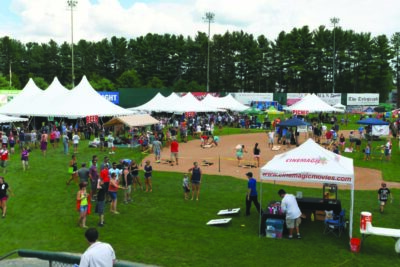 baseball field filled with event tents during beer festival, people participating in activities