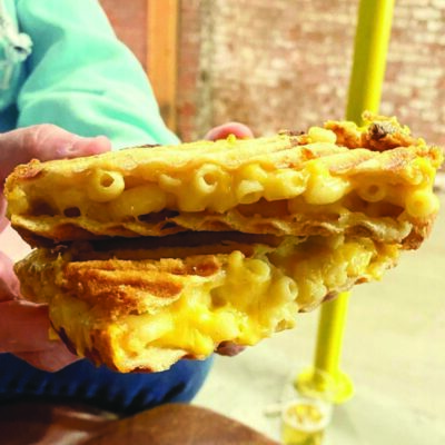 hands holding a mac and cheese sandwich