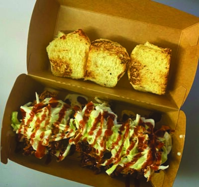 takeout box with barbequed meat and slaw, side of toasted bread