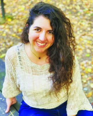 portrait of woman sitting outside, yellow leaves on ground