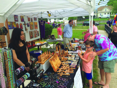young boy and adult looking at items at a craft booth at outdoor event