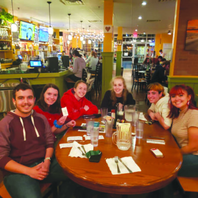group of friends sitting around table at restaurant at trivia night