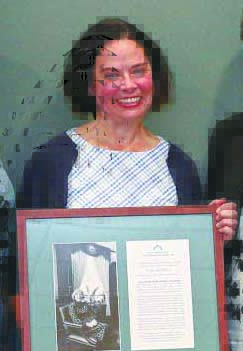 woman holding framed award, smilling