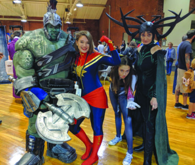 Man, woman, and two girls posing together in cosplay costumes at event
