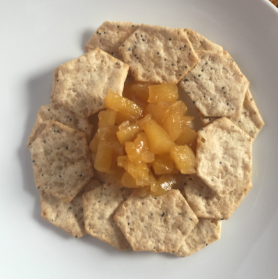 mound of pineapple jam surrounded by circle of crackers on plate