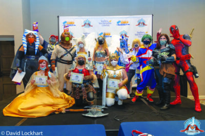 group of people in cosplay posing with their contest winner award certificates