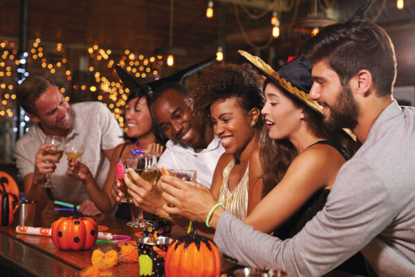 A group of diverse, young party goer's celebrating Halloween in a bar.