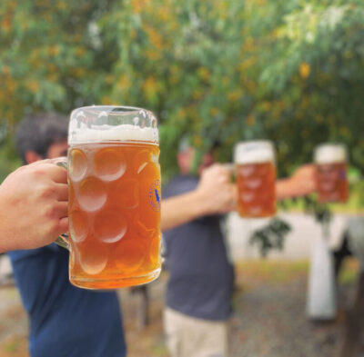 Arms extended out, holding large glass steins of beer in a Stein Holding competition. Ohh buddy whose going to tap out first?