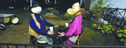 a man and woman scarecrow set up at outdoor table as if drinking coffee