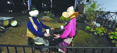 a man and woman scarecrow set up at outdoor table as if drinking coffee