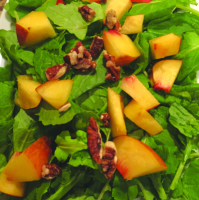 cut peaches and pecans on arugula