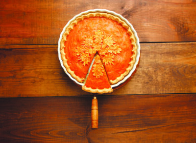 Traditional american fresh round bright orange homemade pumpkin pie in baking dish on wooden table