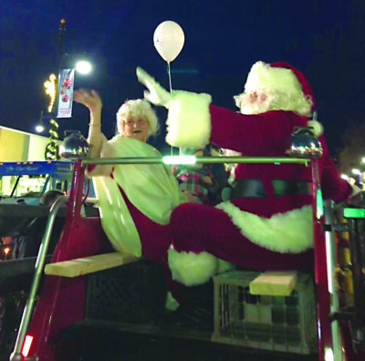 man and woman dressed as Mr. and Mrs. Santa Claus istting on float during parade