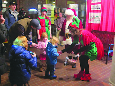 people dressed as Santa and elves handing out candy to young children