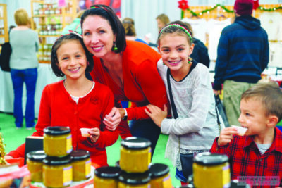 woman at event center with 2 girls and a young boy standing behind food display