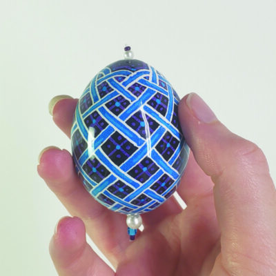 Hand holding painted decorative egg ornament