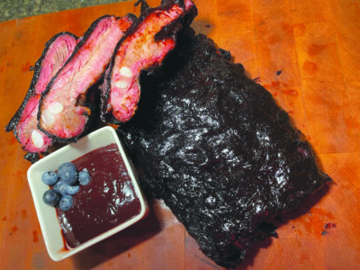 rack of ribs on table beside bowl with sauce and blueberries