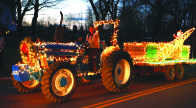 woman sitting on tractor decorated with white christmas lights.