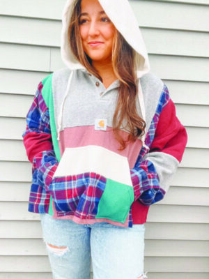 woman modeling upcycled hoodie with  multiple colored flannel sleeves and front pocket