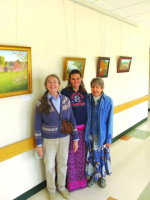 3 women standing in front of wall with hanging art