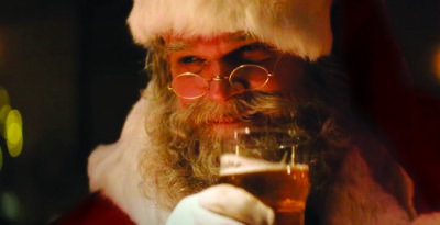 traditional santa with hat, beard and glasses, raising glass of beer to lips