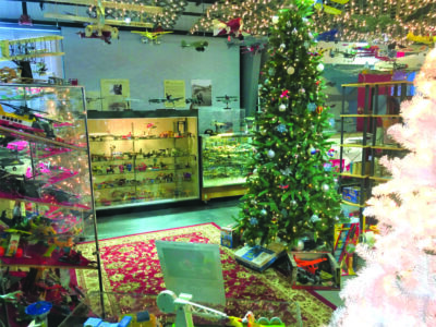 view inside aviation museum displaying cases of toy airplanes, space decorated with christmas tree and garland for holiday event