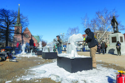 people carving ice sculptures in town square