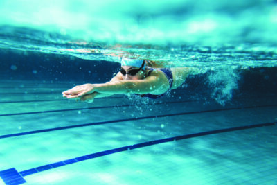Female swimmer at the swimming pool. Underwater photo.