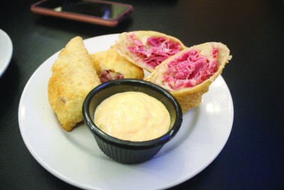 plate contained 3 egg triangular egg rolls filled with beef, one cut in half to see inside, small dish of dipping sauce