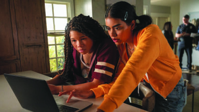 scene from Missing, two teens looking at computer
